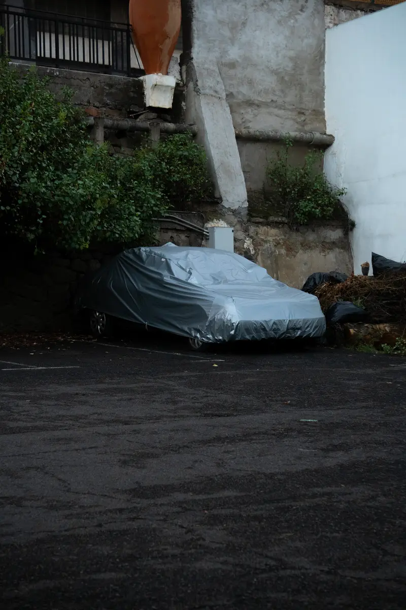 Un'automobile coperta da un telo in un cortile