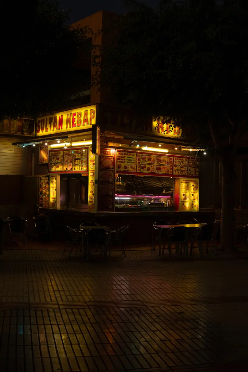 Un chiosco di kebab illuminato al neon di notte