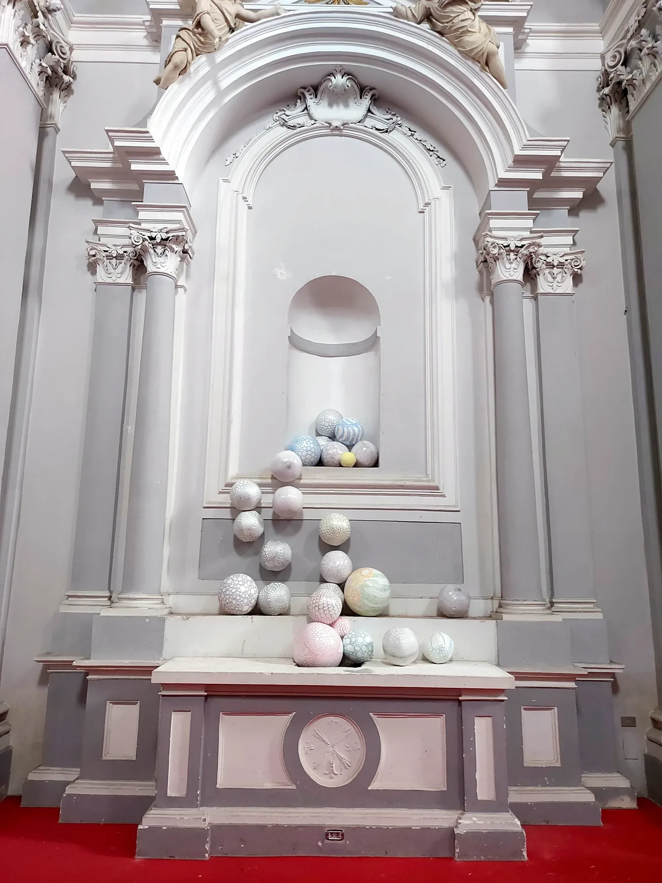 Sfere di ceramica decorate che scendono dalla nicchia di un altare barocco bianco