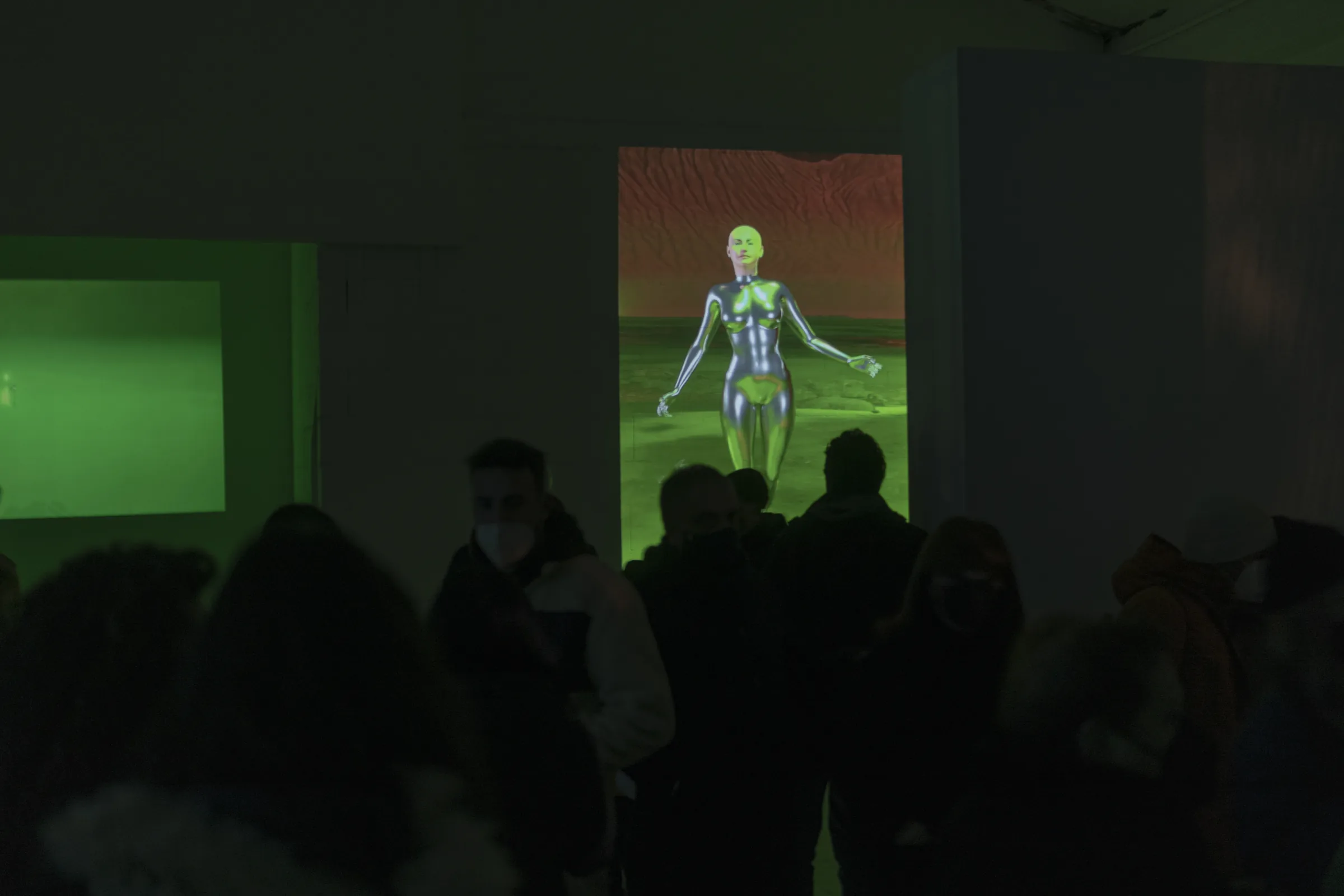 Un avatar argentato su uno schermo verticale, nella sala buia piena di gente
