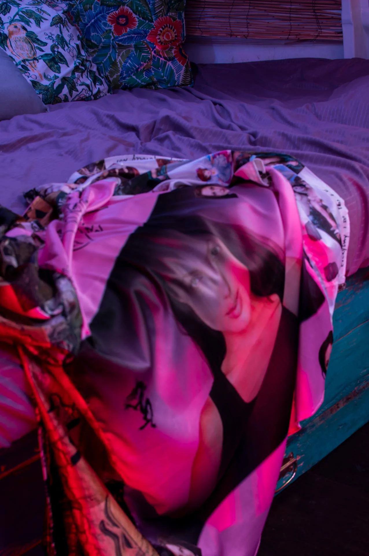 Un telo stampato con un ritratto, steso su un letto in luce rosa