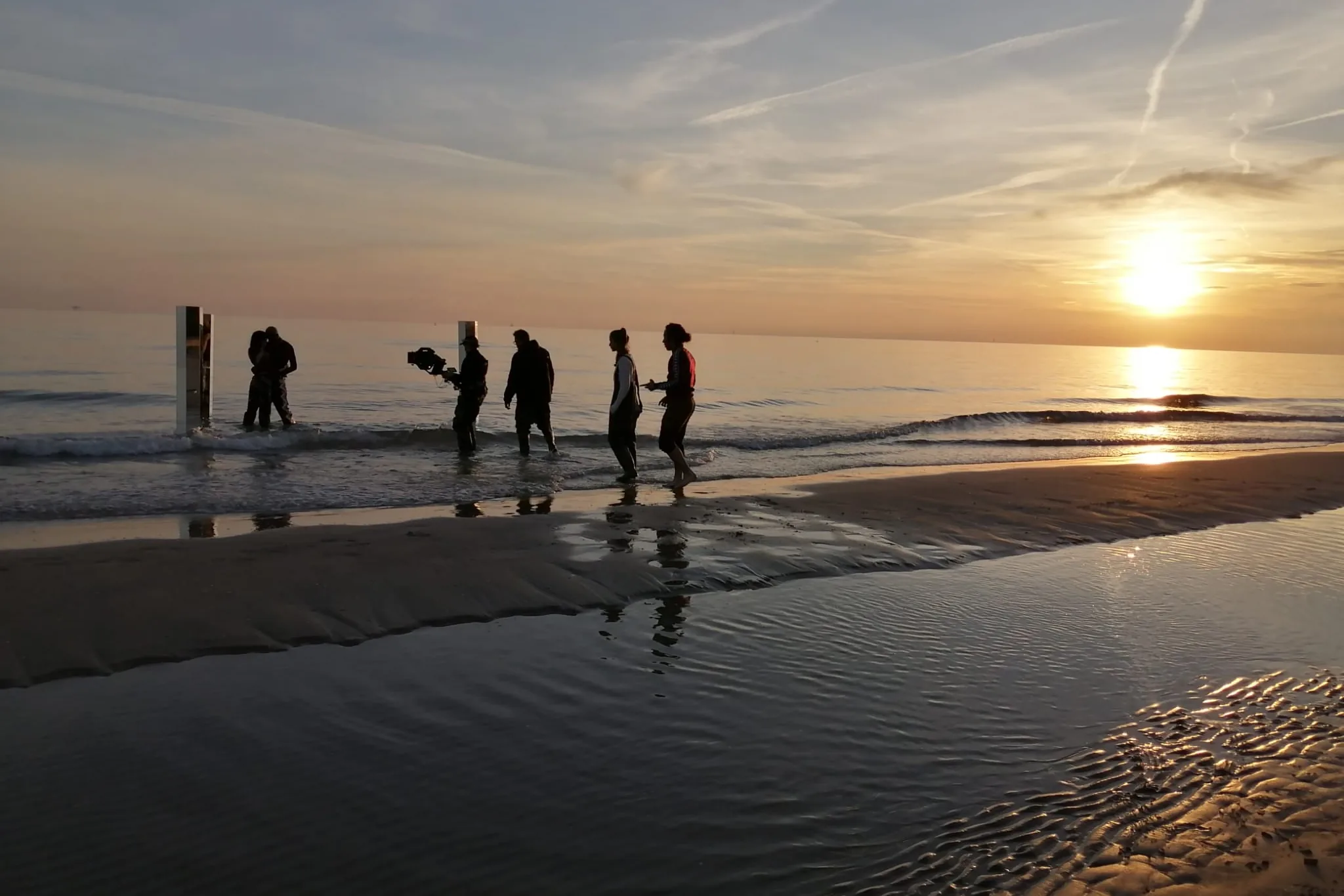 La troupe sulla battigia al sorgere del sole, fra le colonne di specchio