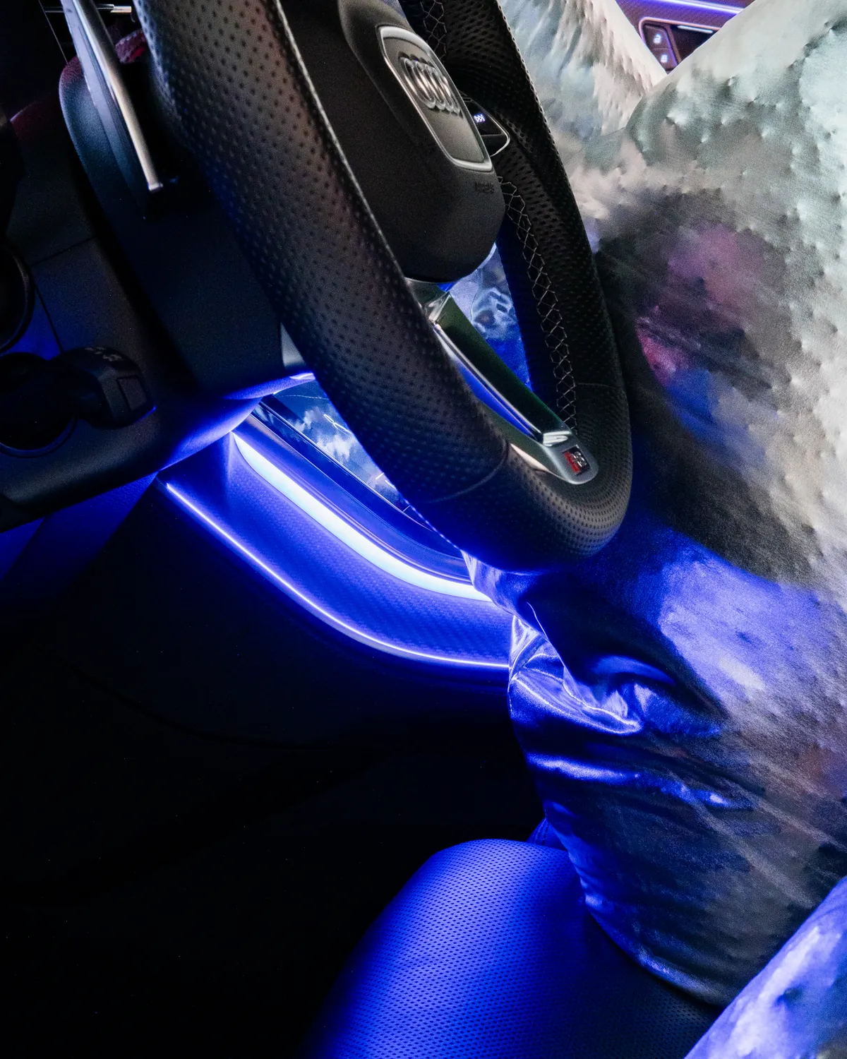 Il volante e l'abitacolo in luce blu, con la scultura argentata dietro